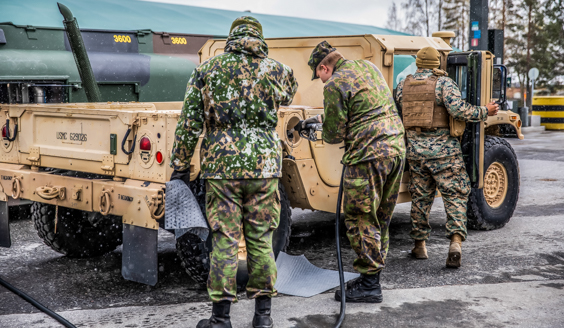 Sotilaat tankkaavat vaaleanruskeaa lava-ajoneuvoa