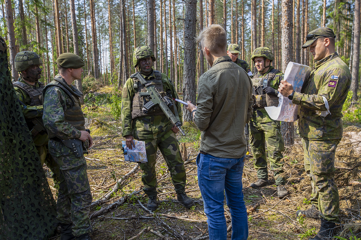 Sotilaat keskustelevat toimittajan kanssa metsässä