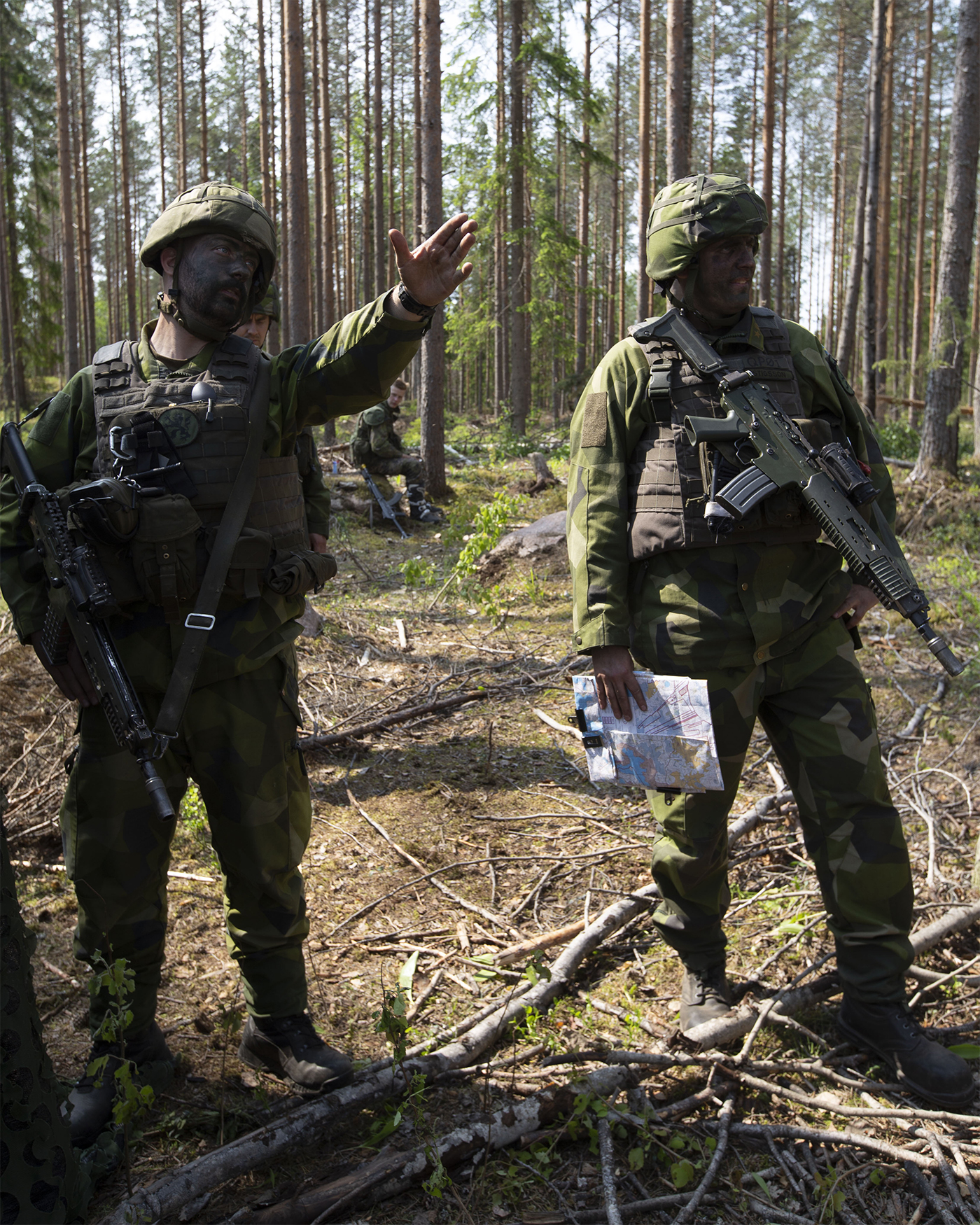 Sotilas osoittaa kädellä suuntaa muille sotilaille metsässä