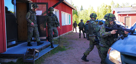 Sotilaat suojaavat rakennuksesta ulos tulevaa sotilashenkilöä