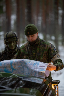 Maastopukuinen sotilas lukee karttaa.