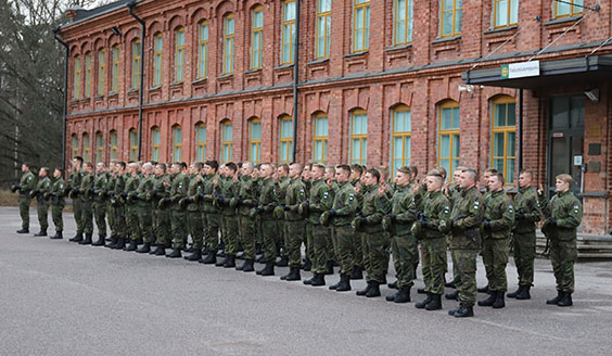 Sotilaat seisovat kolmirivissä lakit kädessä