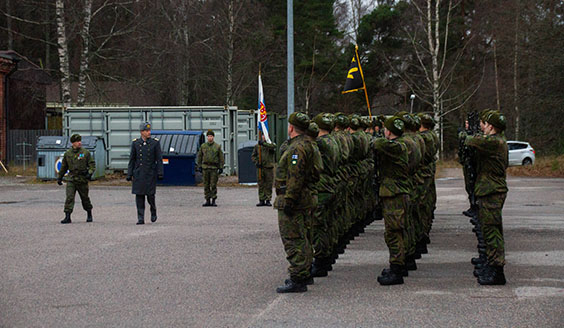 Sotilaat seisovat kolmirivissä kun komentaja tarkastaa joukot