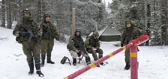 Sotilaa seisovat ja istuvat lumisessa metsässä