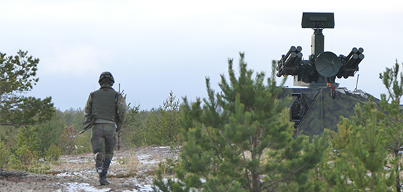 Sotilas juoksee ilmatorjuntaohjuslavettia kohti metsässä