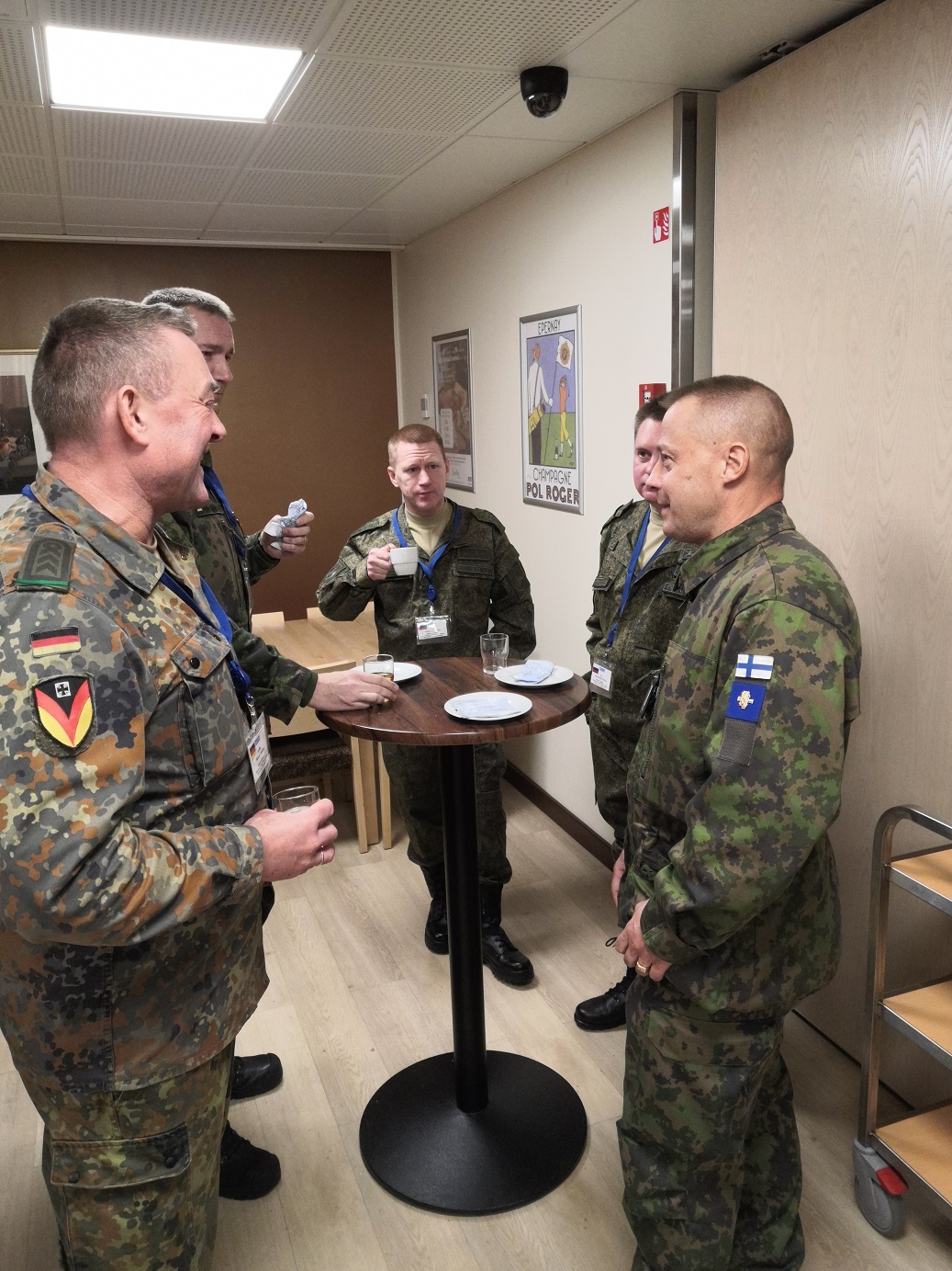 Kuvassa majuri Toivanen seisoo ja keskustelee yhdessä ulkomaalaisten sotilaiden kanssa. Kuvassa on suomalaisten sotilaiden lisäksi saksalainen ja kaksi venäläistä sotilasta.