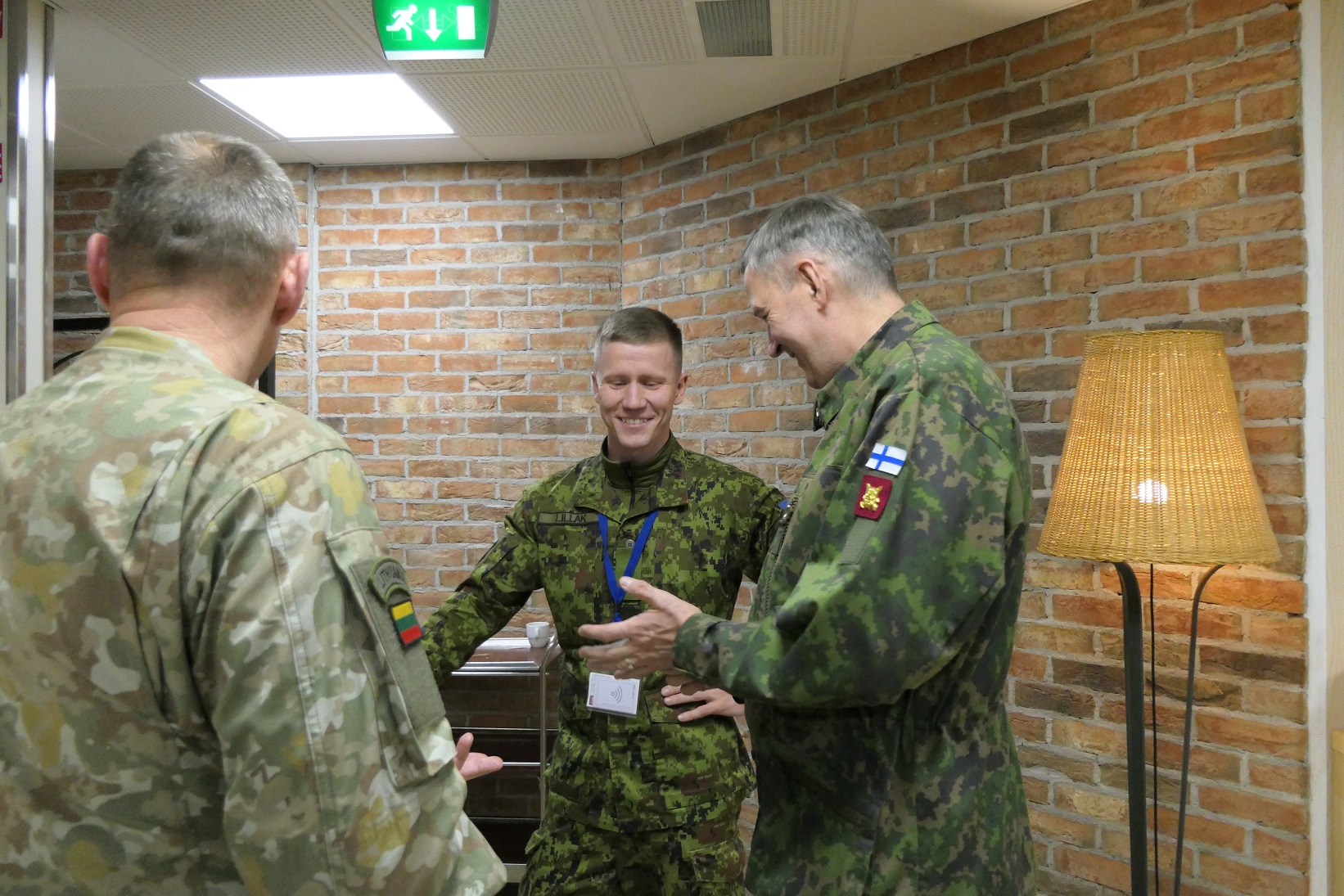 Suomalainen kenraali keskustelee hymyillen virolaisen asevalvontaupseerin kanssa, etualalla näkyy liettualainen asevalvontaupseeri (selin).