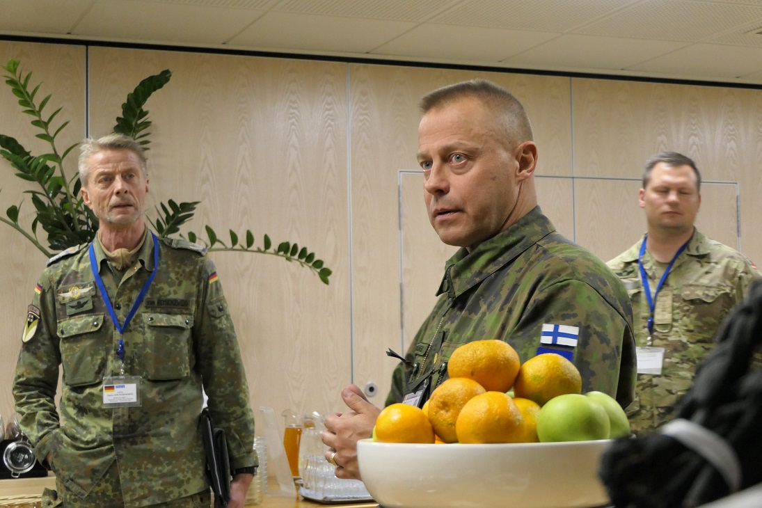 Keskella Suomen asevalvontaupseeri Toivanen ja häntä kuuntelevat Saksan ETYJ-tarkkailija ja takana myös Puolan ETYJ-tarkkailija, kaikki sotilashenkilöitä maastopuvuissa.
