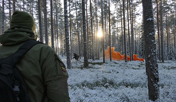 Liettuan ETYJ-tarkkailija katsoo oranssia savua metsässä lähitaistelutilanteessa.