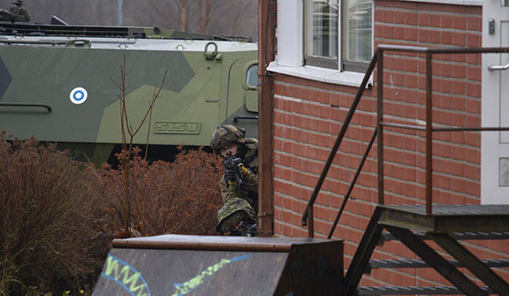 Sotilaat tähtäävät rakennuksen kulman takana suojassa rynnäkkökivääreillä