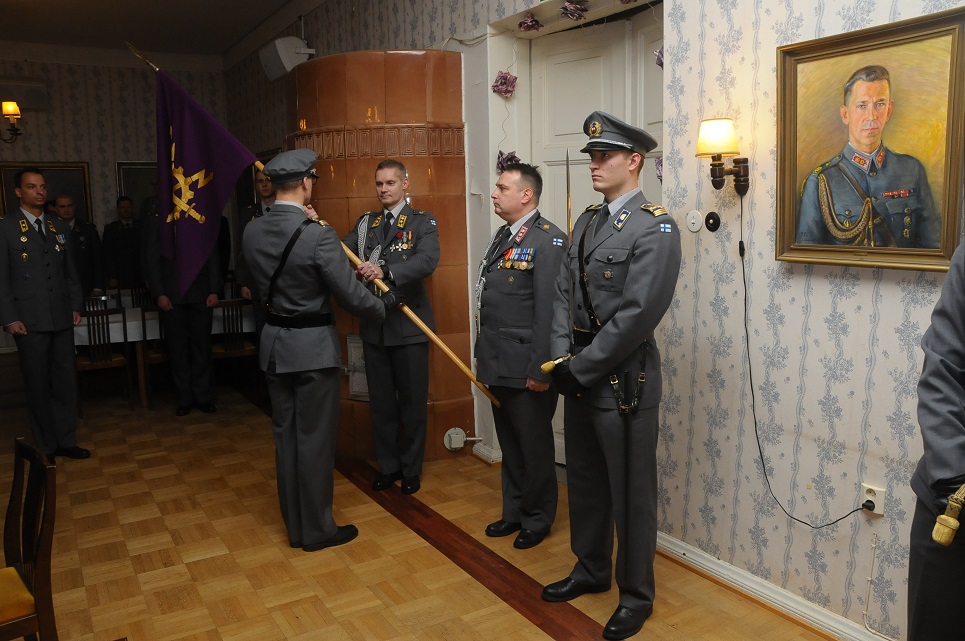 Kuvassa sotilashenkilö luovuttaa Viestikoulun lipun toiselle sotilashenkilölle.