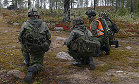 Sotilaat ja huomioliivillinen kouluttaja korkeassa polviasennossa metsässä