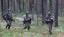 Kolme sotilasta etenevät metsässä