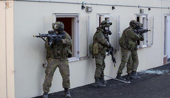 Sotilaita rakennuksen seinustalla suojanaamarit päässä