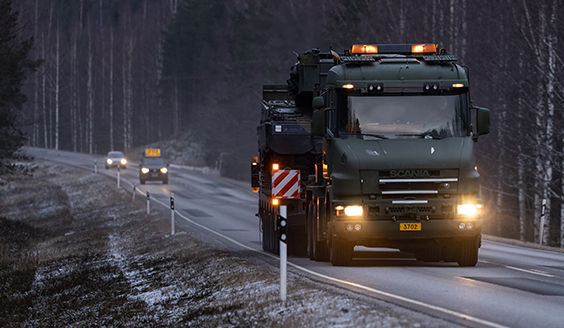 Puolustusvoimien vihreä kuorma-auto ajaa maantiellä kohti perässään yli leveä kuljetus -huomiomerkillä varustettu maastoauto.