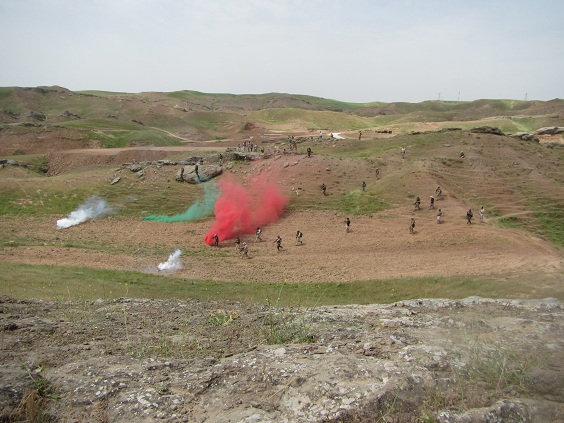 Ilmakuva sotilaista harjoituksessa, maahan on heitetty eri värisiä savuja