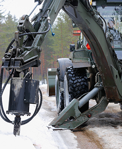 Kaivinkone poraa reikää tien viereen