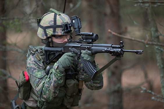 The soldier is aiming through the red dot sight