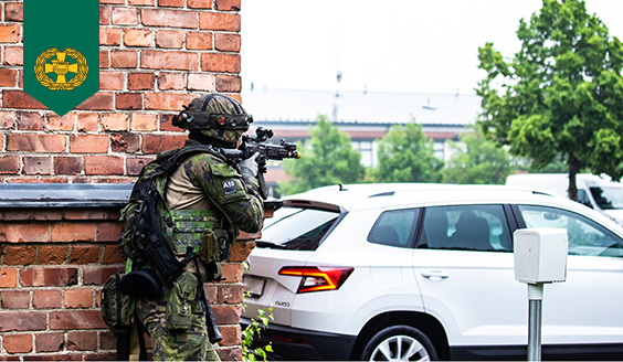 En stadskanare siktar med ett anfallsgevär från runt hörnet