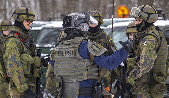 Police officer in heavy gear is talking to the soldiers