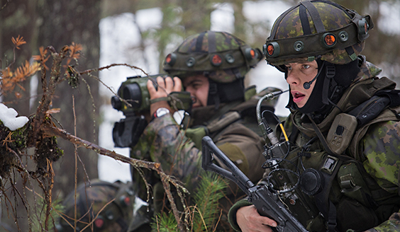 Kaksi sotilasta metsässä joista toinen tähystää kiikareilla