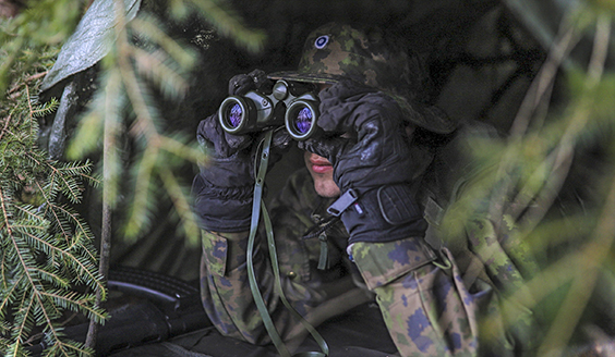 A soldier looks through binoculars 