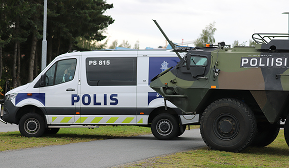 Poliisiauto ja Puolustusvoimien panssariajoneuvo vierekkäin valvomassa sisääntuloliikennettä. Panssariajoneuvo on merkitty poliisin tunnuksin.