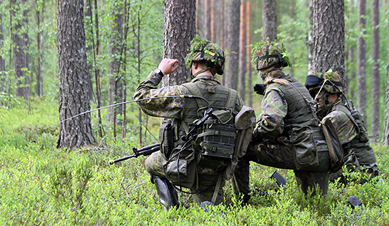 Kolme sotilasta metsässä polviasennossa