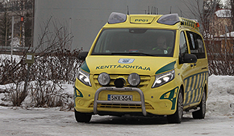 Keltainen pakettiauto jossa on hälytysvalot ja konepellissä lukee