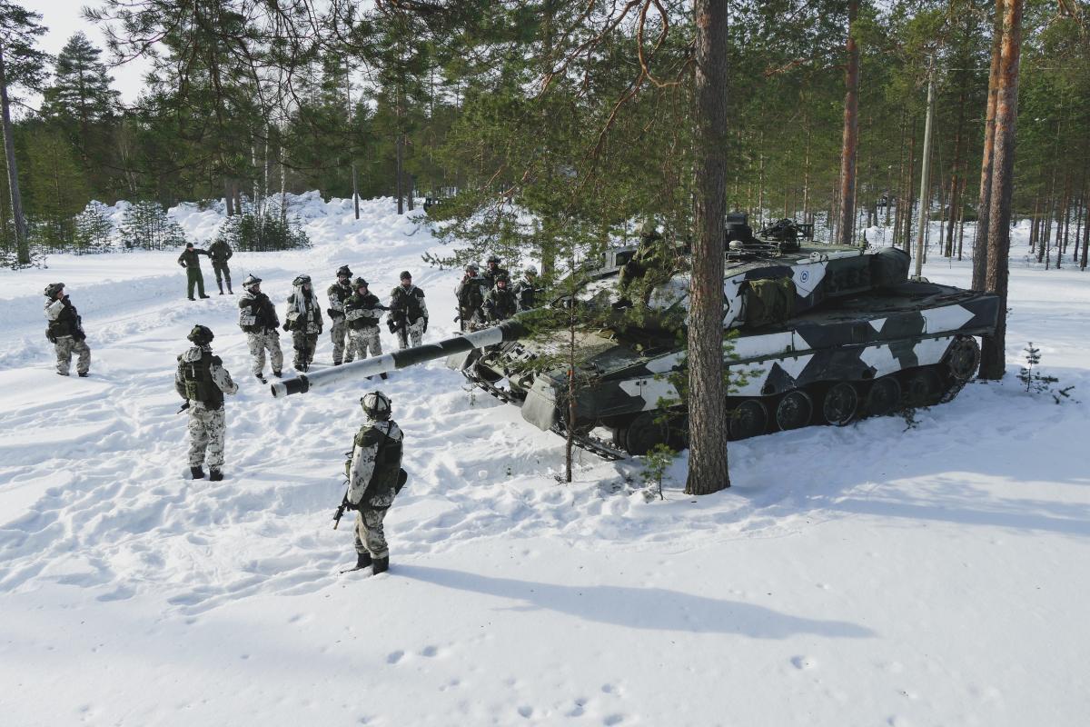Panssarivaunu ja sotilaita lumisessa metsässä