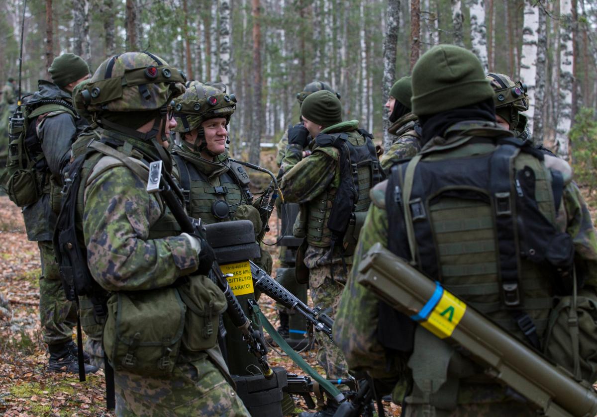 Sotilaat keskustelevat metsässä. Aseinaan rynnäkkökivääreitä, kertasinkoja sekä panssarintorjuntaohjuksia.