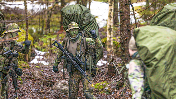 Sotilaat metsässä mukanaan isot rinkat ja rynnäkkökiväärit.