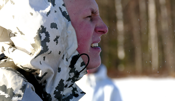 En soldat i en snödräkt kryper ögonen i solen