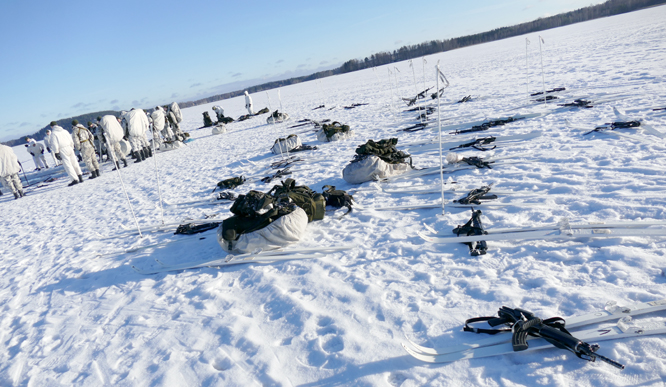 Skis and backpacks lined up on the snow