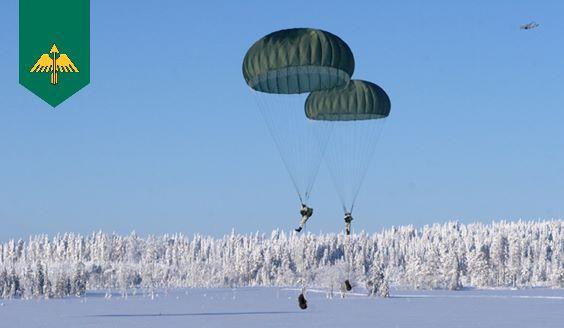 Fallskärmshoppare landar med fallskärmar på ett snöig fält