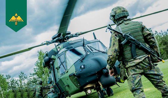 A soldier stands in front of a helicopter