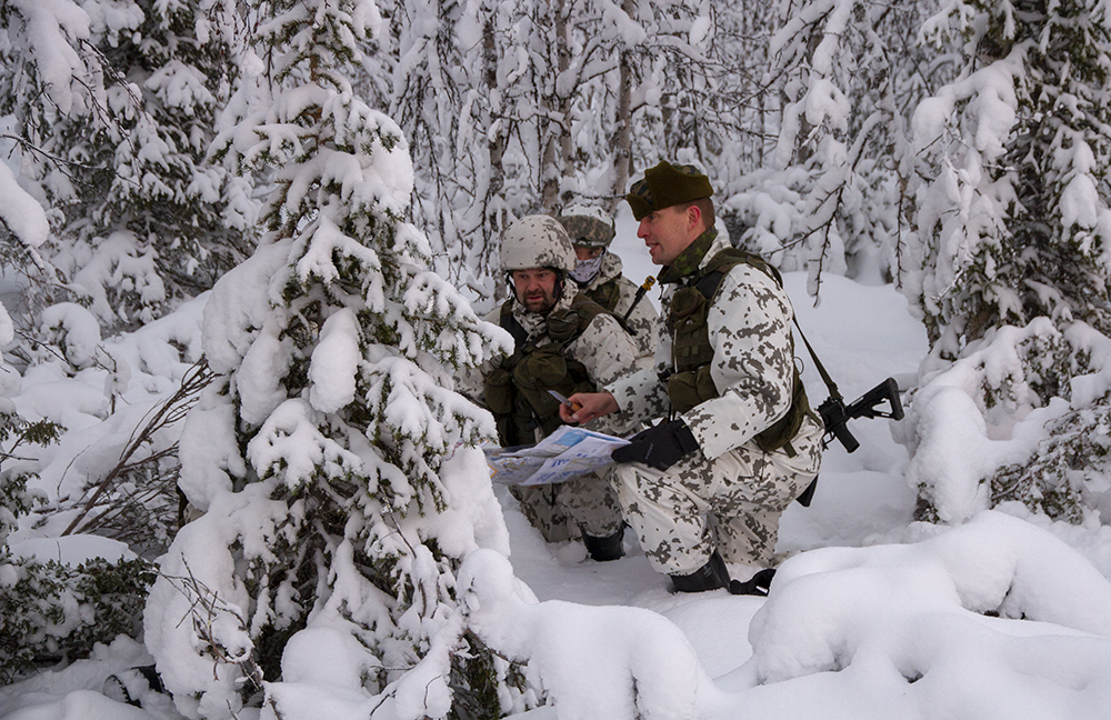 Kolme sotilasta lumisess metsässä, komentaja antaa käskyn joukoille.