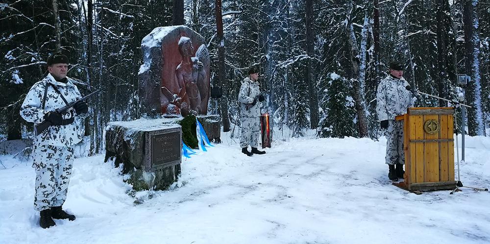 Pelkosenniemen taistelun muistomerkillä kolme sotilasta, jätkänkynttilä taustalla ja seppele laskettu muistomerkille.