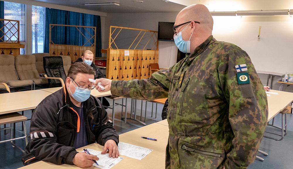 Kapteeni mittaa reserviläiseltä kuumeen otsasta.