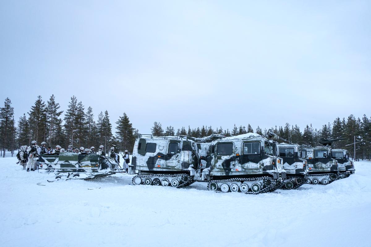 Neljä tela-ajoneuvoa ja varusmiehiä lähdössä harjoitukseen talvella.