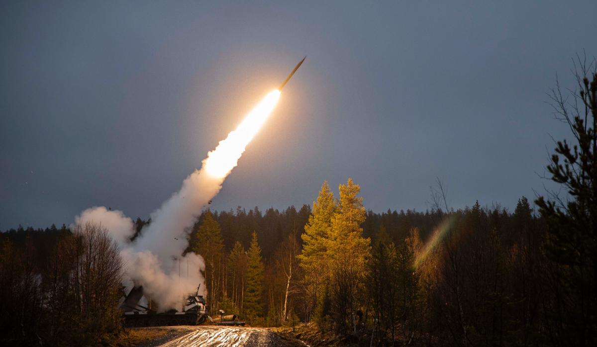 Kuva jossa raskas raketinheitin on tiellä ja ampuu raketin ilmaan.