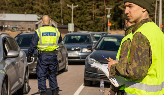 kuva, jossa varusmies etualalla laskee liikennettä poliisin tukena