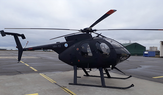 Musta MD500-helikopteri kentällä