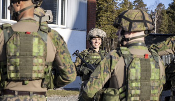 kuva jossa naissotilas taisteluvarustuksessa joukon osana