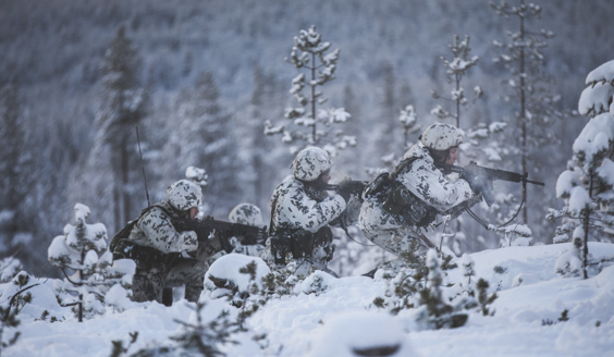 Kuva jossa varusmiehiä etenee ase ylhäällä lumisessa maastossa.