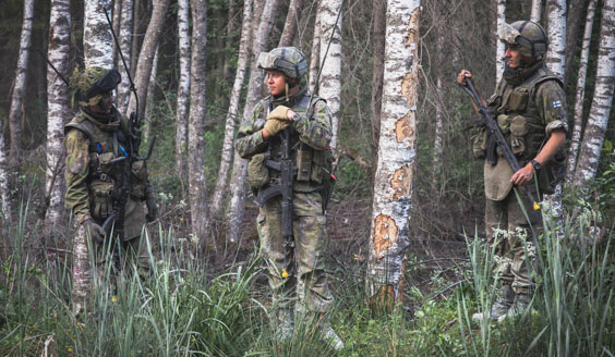kuva, jossa kolme varusmiestä keskustelee keskenään metsässä