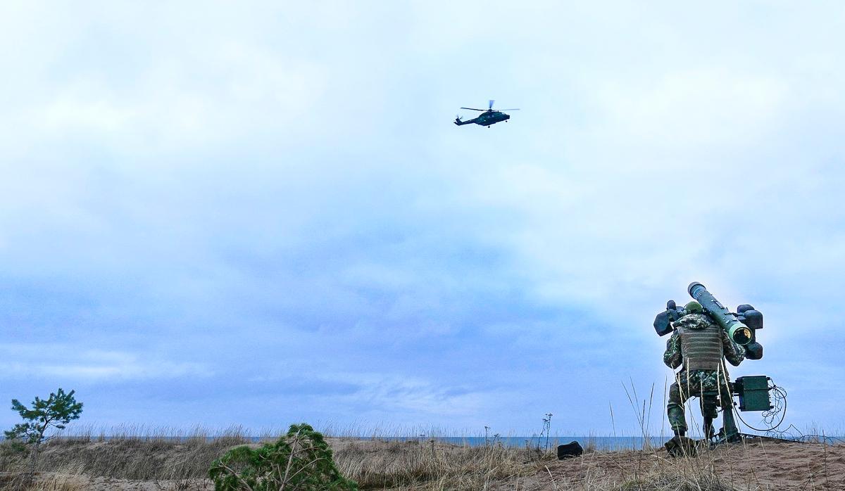 kuva, jossa maasta tähdään ilmatorjunta-aseella taivaalla lentävää helikopteria