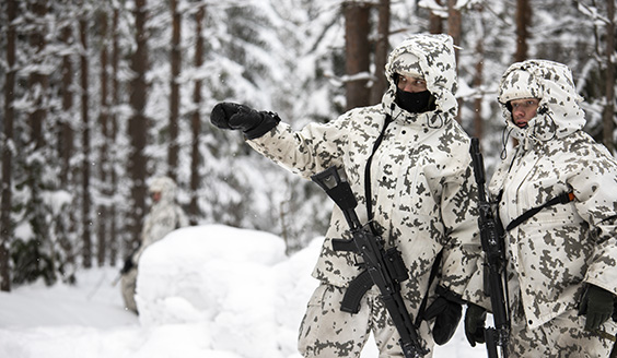 Lumipukuisia sotilaita talvisessa metsässä