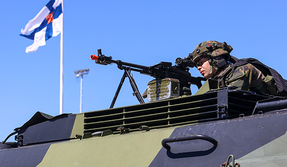 Varusmies tähtää PKM-konekiväärillä panssaroidun ajoneuvon katolla.