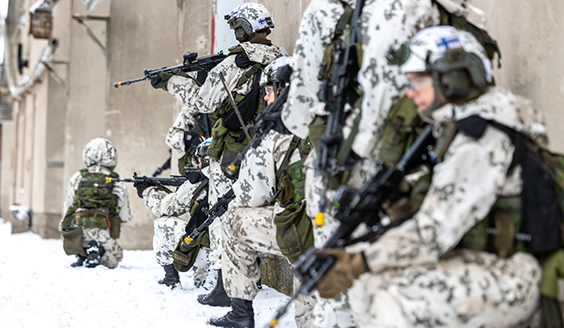 Sotilaita lumipuvuissa rynnäkkökiväärien kanssa